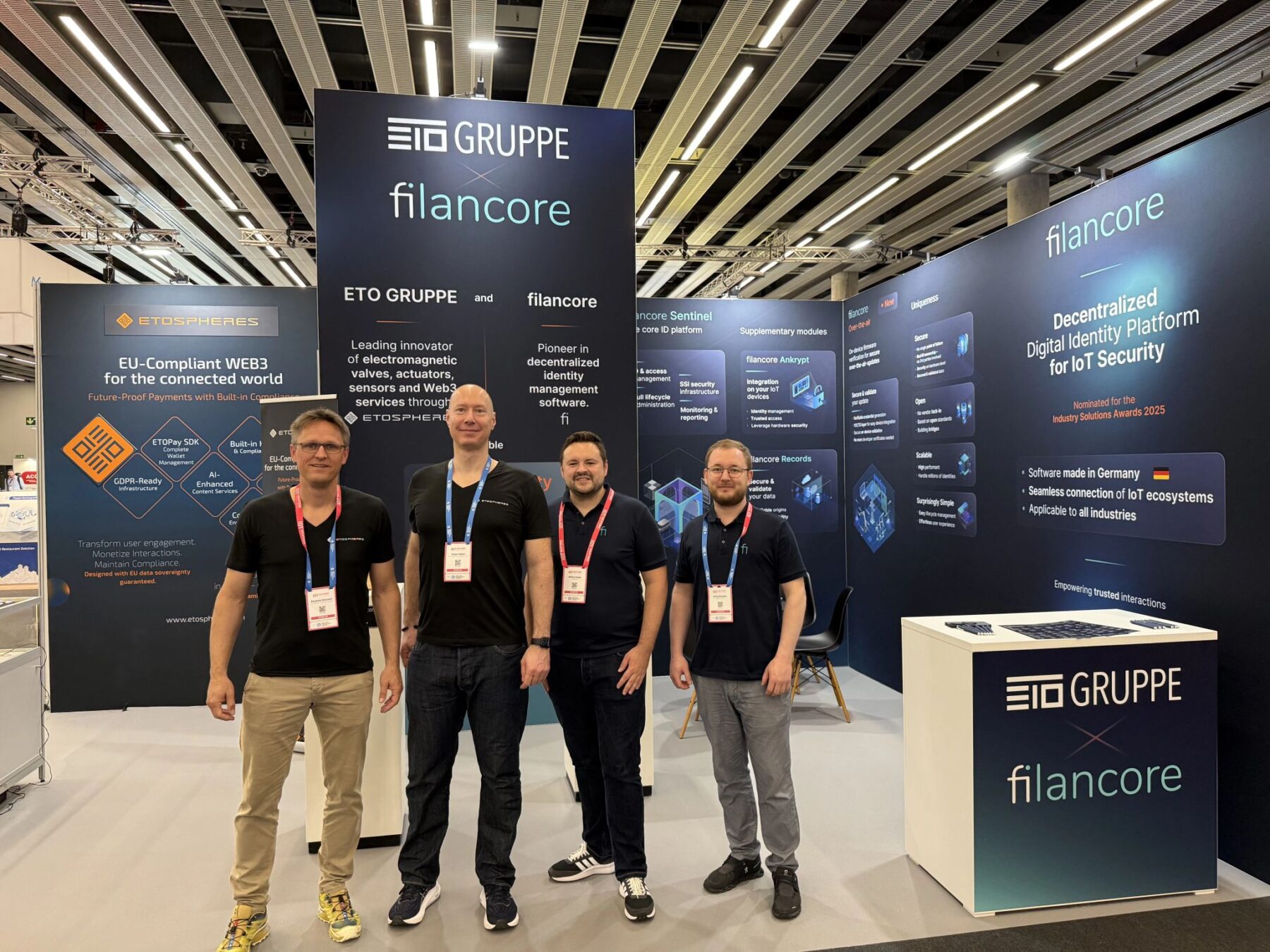 Benjamin Bönisch and Holger Köther from ETO Gruppe and Markus Soppa and Andrej Russkov in front of the joint booth at IoT Solutions World Congress in Barcelona